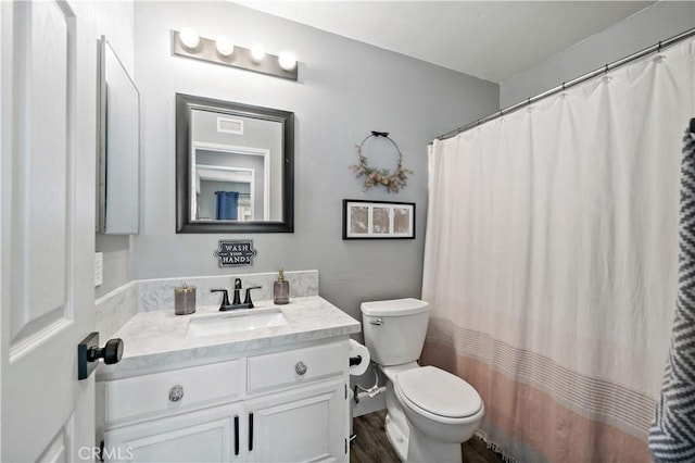 bathroom with toilet, wood finished floors, and vanity