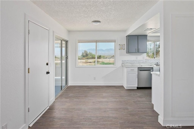 kitchen featuring dishwasher, a textured ceiling, dark wood-type flooring, light countertops, and baseboards