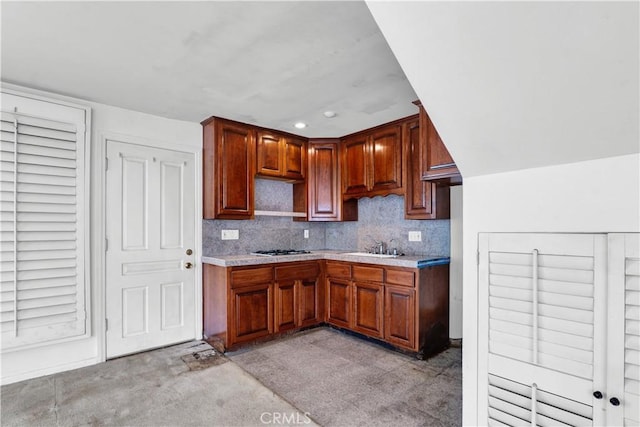 kitchen featuring backsplash, gas cooktop, light countertops, and a sink