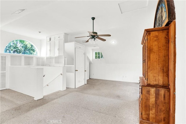 interior space with light colored carpet, ceiling fan, visible vents, and vaulted ceiling