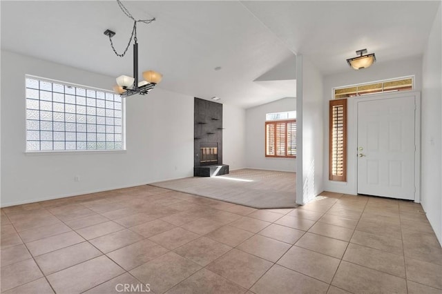 tiled foyer featuring an inviting chandelier, baseboards, vaulted ceiling, and a fireplace