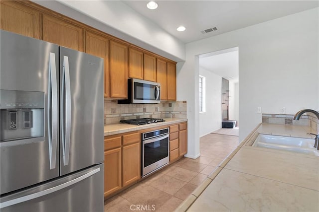kitchen featuring light tile patterned floors, decorative backsplash, a sink, appliances with stainless steel finishes, and visible vents