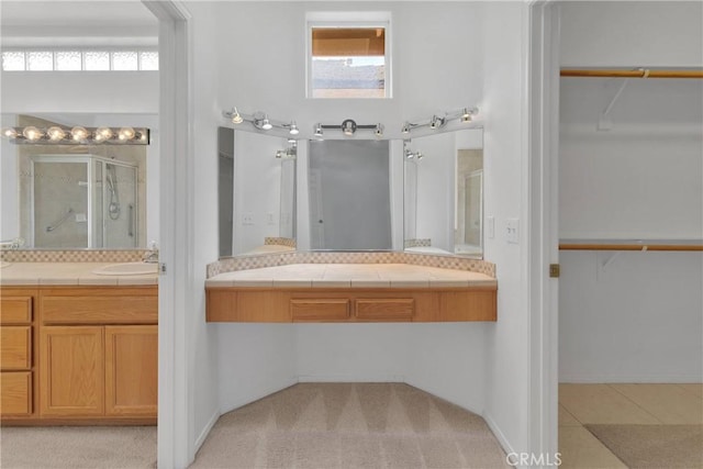 bathroom with vanity, a stall shower, and a walk in closet