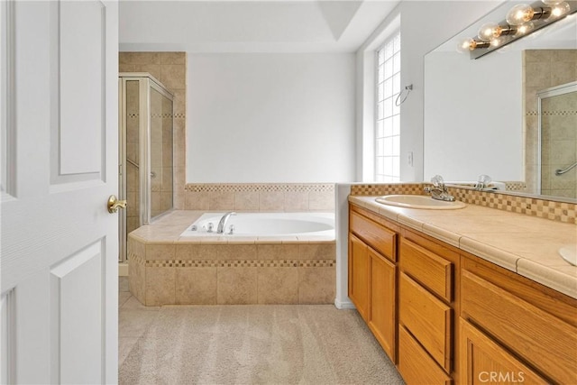 bathroom with double vanity, a garden tub, a shower stall, and a sink