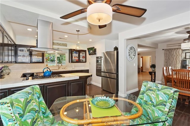 kitchen with glass insert cabinets, stainless steel appliances, dark brown cabinetry, tile countertops, and island exhaust hood