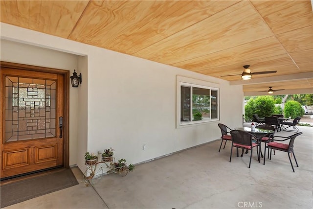 view of exterior entry featuring stucco siding, outdoor dining space, and ceiling fan