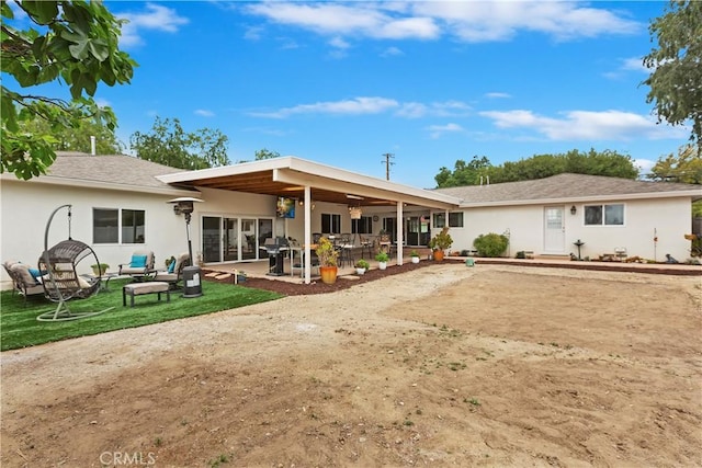 rear view of house with an outdoor living space, stucco siding, and a patio area