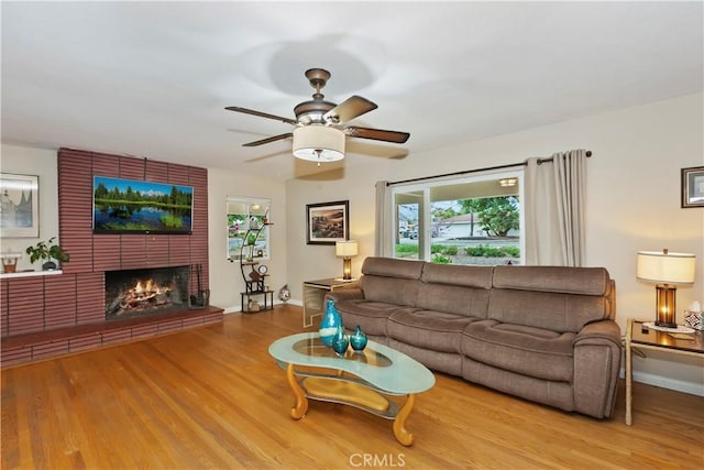 living room with a ceiling fan, baseboards, wood finished floors, and a fireplace