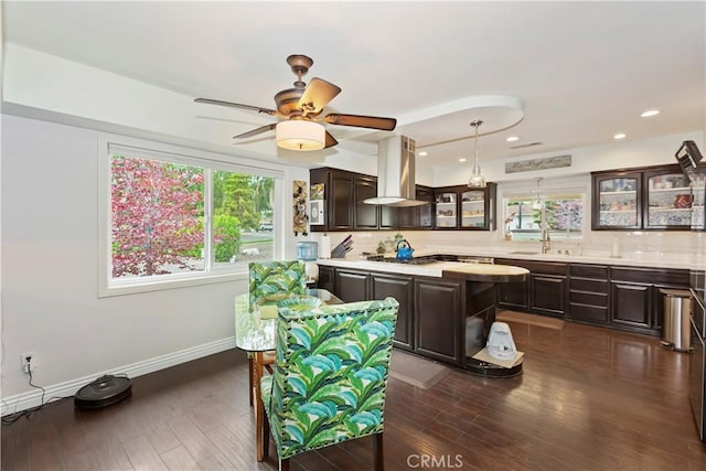 kitchen with glass insert cabinets, dark brown cabinetry, island range hood, and light countertops