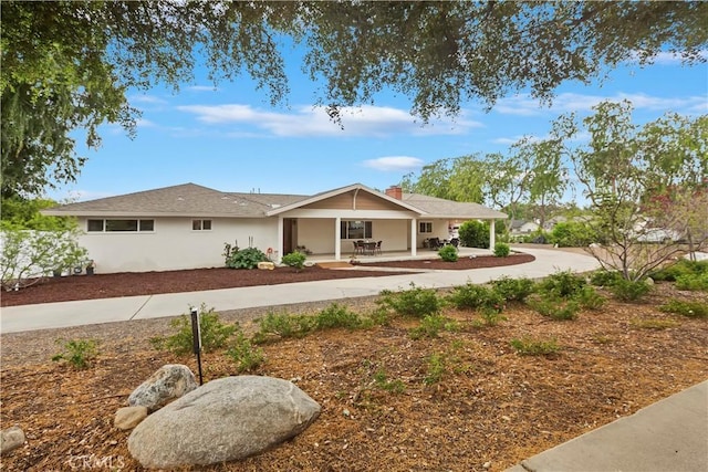 ranch-style house with stucco siding, a porch, and curved driveway