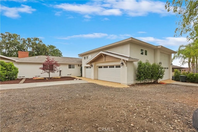 traditional-style home featuring a garage, a chimney, stucco siding, and driveway