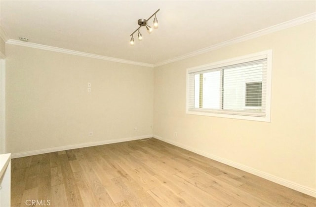unfurnished room featuring baseboards, light wood finished floors, and crown molding
