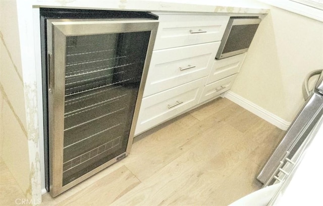 interior details with wine cooler, wood finished floors, and baseboards