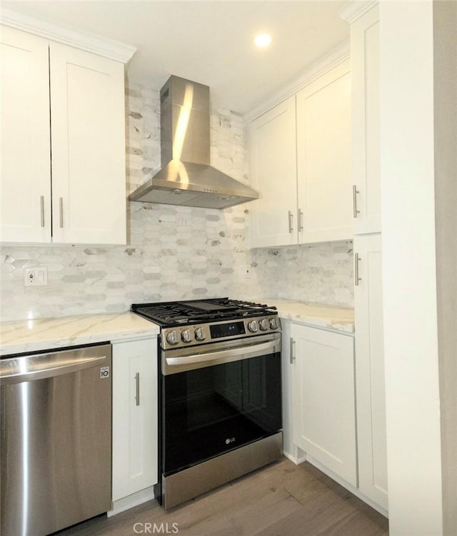 kitchen featuring white cabinetry, tasteful backsplash, wall chimney exhaust hood, and appliances with stainless steel finishes