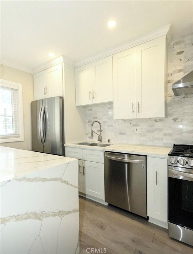kitchen with ornamental molding, a sink, appliances with stainless steel finishes, and tasteful backsplash