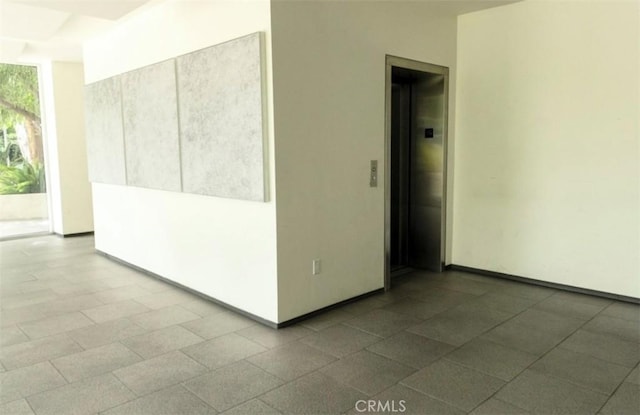 spare room with elevator and baseboards