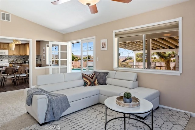 living area featuring light carpet, baseboards, visible vents, a ceiling fan, and lofted ceiling