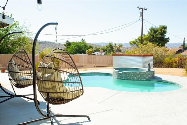 view of swimming pool with fence, a patio area, and a pool with connected hot tub