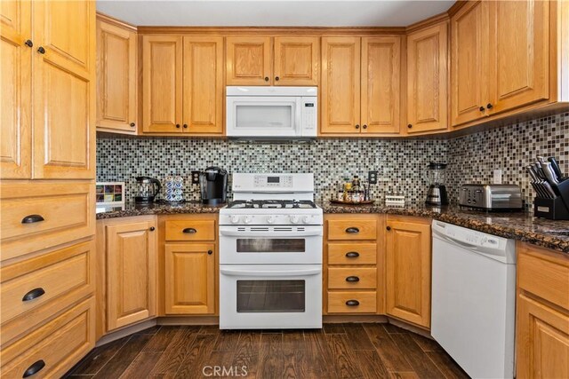 kitchen featuring dark wood finished floors, dark stone countertops, white appliances, and decorative backsplash