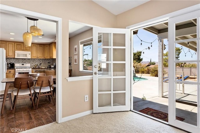 doorway featuring lofted ceiling, a wealth of natural light, wood finished floors, and baseboards