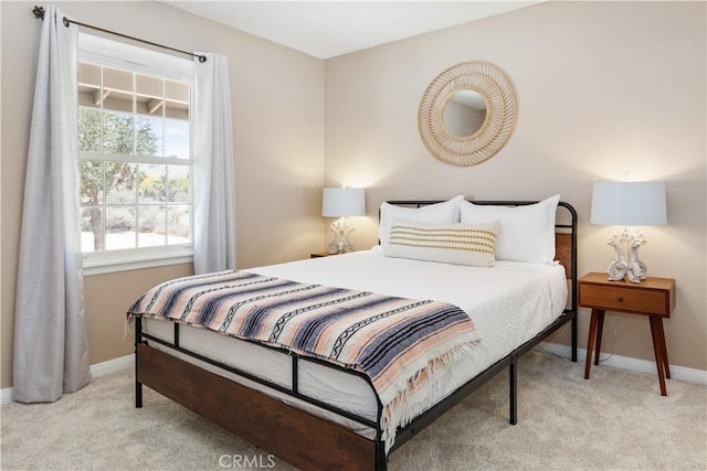 bedroom with light colored carpet and baseboards