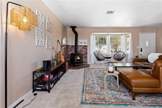carpeted living area featuring a wood stove, visible vents, and baseboards