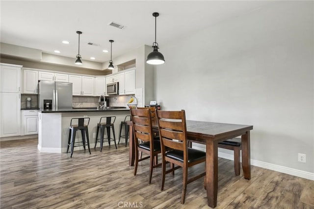 dining room with wood finished floors, visible vents, recessed lighting, and baseboards