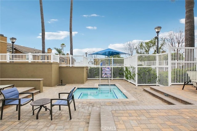 view of swimming pool with fence, a hot tub, and a patio area