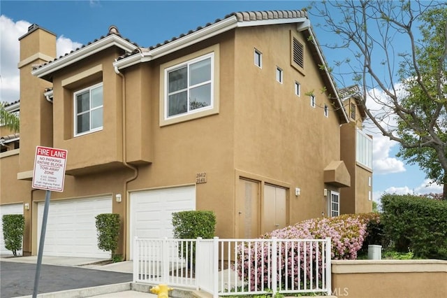 view of front of home featuring stucco siding, a chimney, and a garage
