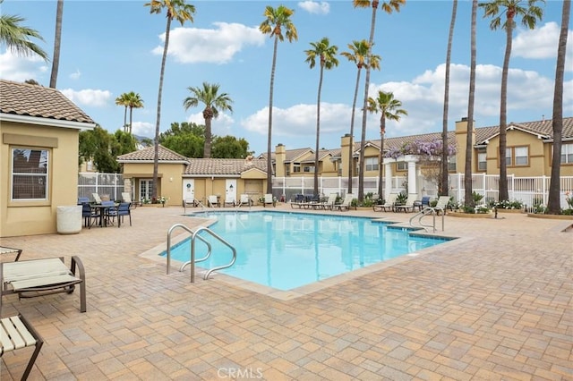 community pool with a residential view, a patio, and fence