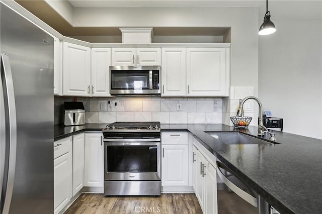 kitchen featuring a sink, white cabinets, wood finished floors, and stainless steel appliances