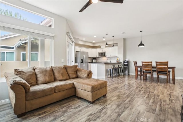 living room featuring a ceiling fan, wood finished floors, and baseboards