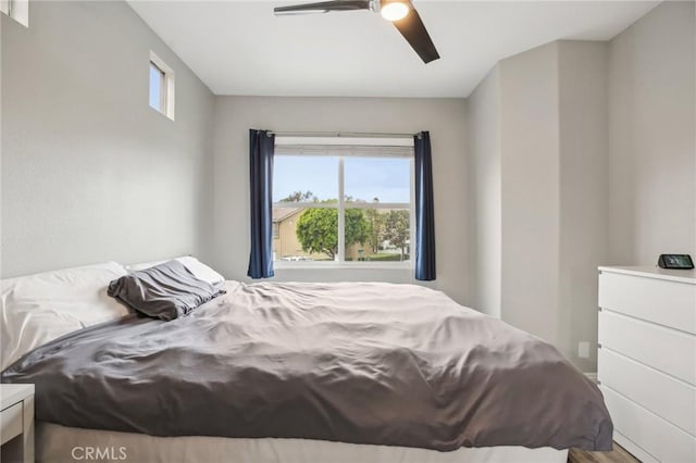 bedroom featuring wood finished floors, ceiling fan, and multiple windows