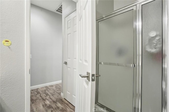 bathroom featuring wood finished floors, visible vents, a stall shower, and baseboards