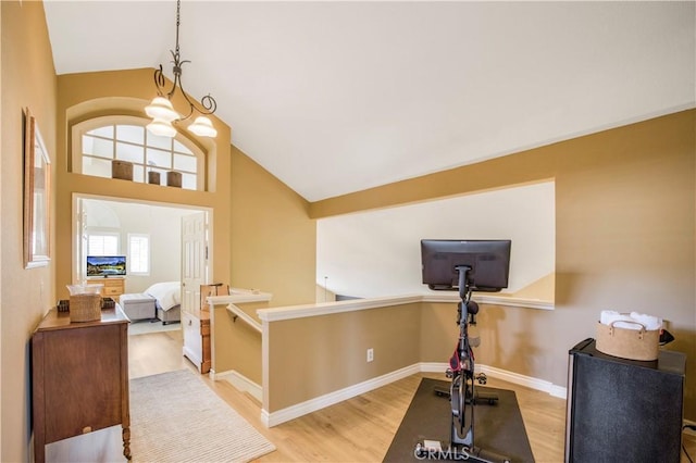 exercise room with baseboards, high vaulted ceiling, and wood finished floors