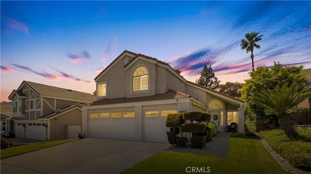 view of front of home featuring driveway, a tiled roof, stucco siding, and an attached garage