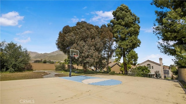 view of sport court featuring a mountain view, basketball court, and fence
