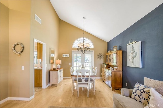 dining space with visible vents, baseboards, an inviting chandelier, light wood-type flooring, and high vaulted ceiling