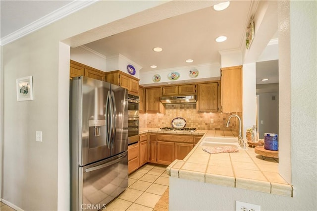 kitchen featuring a sink, under cabinet range hood, tasteful backsplash, tile countertops, and stainless steel fridge with ice dispenser