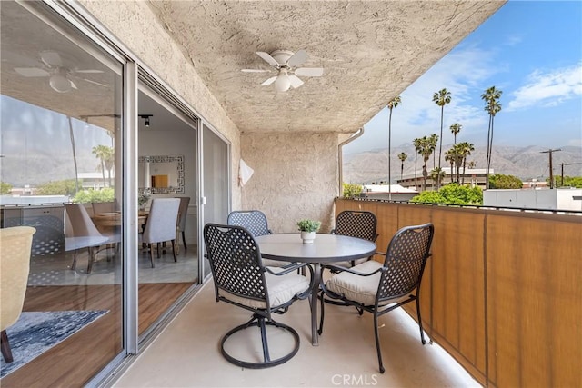 balcony with a mountain view, ceiling fan, and outdoor dining space