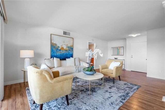 living area featuring visible vents, wood finished floors, and baseboards