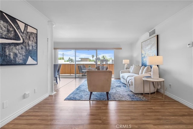 living area with wood finished floors, visible vents, crown molding, and baseboards