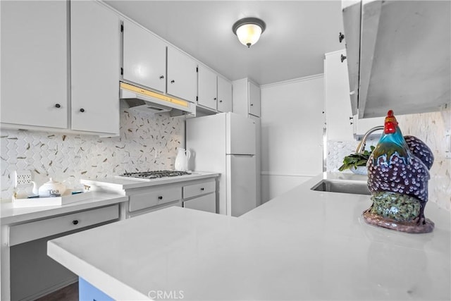 kitchen with light countertops, gas stovetop, freestanding refrigerator, and under cabinet range hood