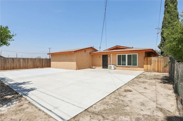rear view of house with a fenced backyard, stucco siding, and a patio area