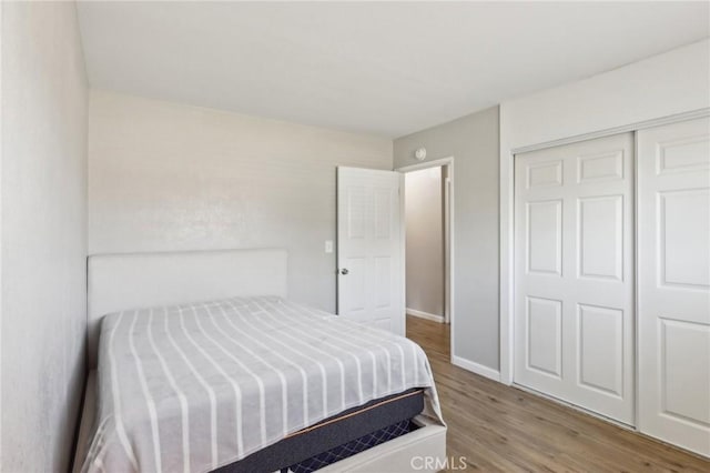 bedroom with a closet, wood finished floors, and baseboards