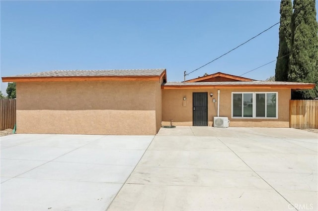 view of front facade featuring a patio, stucco siding, and fence