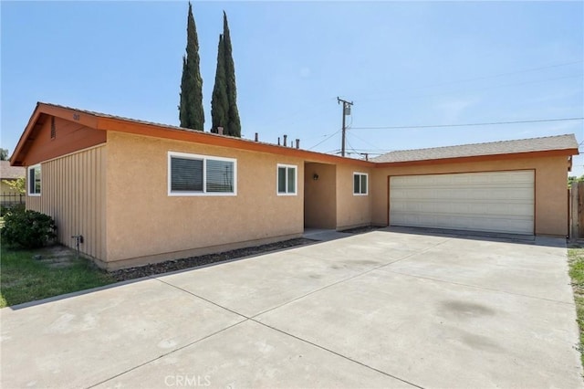 ranch-style house featuring a garage, stucco siding, and concrete driveway