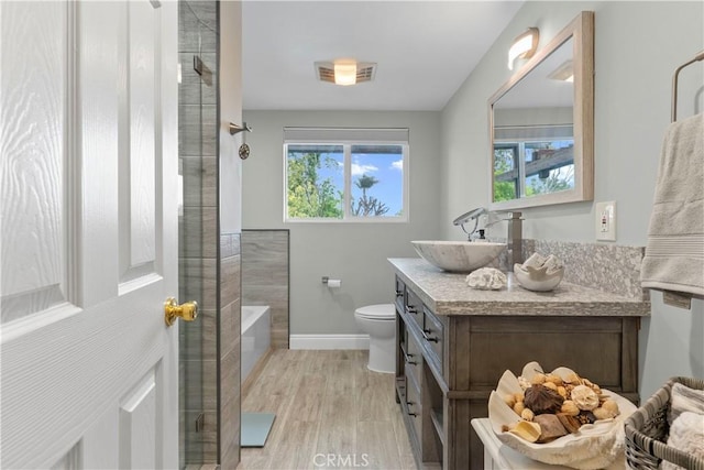 full bath featuring wood finished floors, walk in shower, toilet, vanity, and baseboards