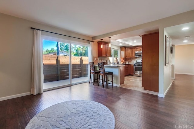 1023 Mimosa Ave, Vista, CA 92081 - kitchen with appliances with stainless steel finishes, a peninsula, brown cabinets, light wood-style flooring, and a raised ceiling