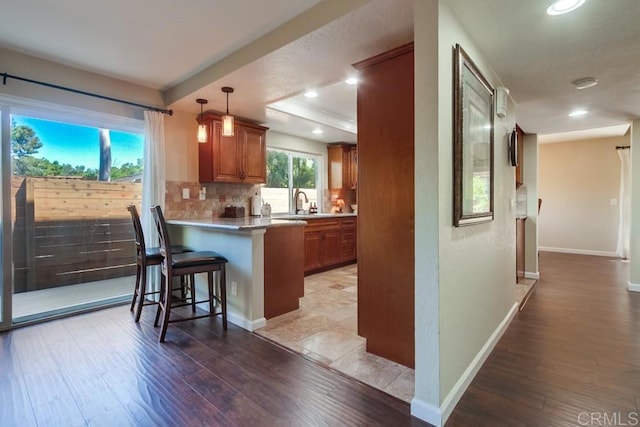 1023 Mimosa Ave, Vista, CA 92081 - kitchen with brown cabinetry, light wood finished floors, a breakfast bar area, tasteful backsplash, and recessed lighting